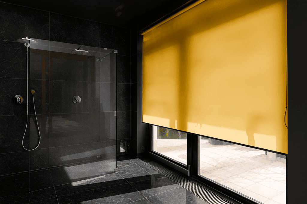 Moderní koupelna s mramorovými obklady a žlutými látkovými roletami do koupelny na velkých oknech.