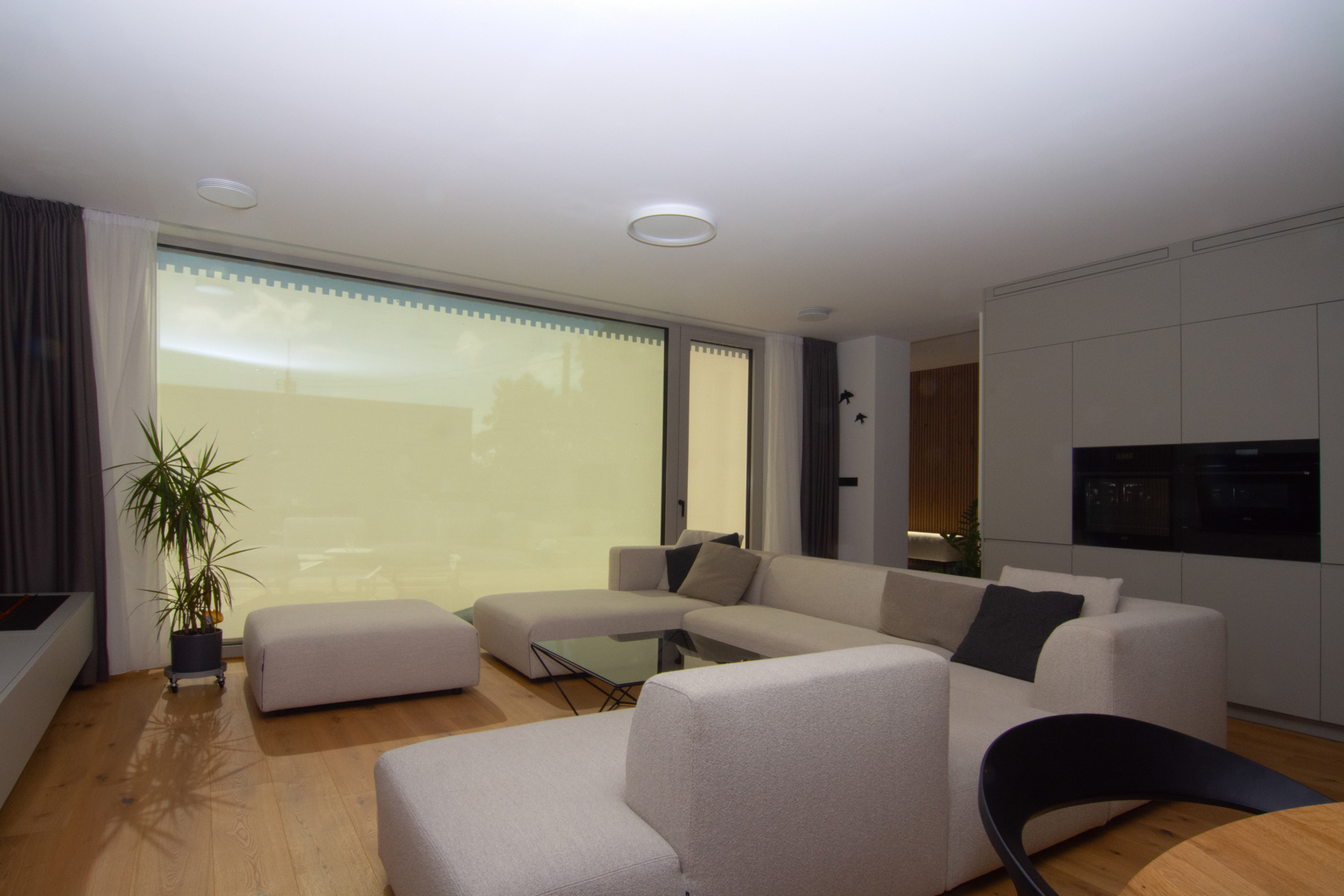 Interiér moderního domu se zataženými screenovými roletami CLIMAX, které filtrují světlo a chrání před přehříváním.