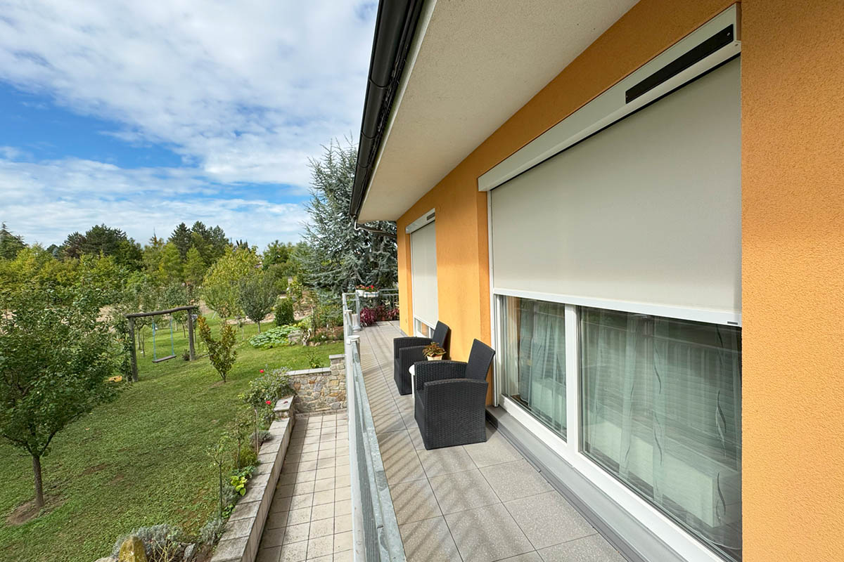 Rodinný dům se solárními screenovými roletami CLIMAX odolnými vůči větru na terase s výhledem do zahrady.