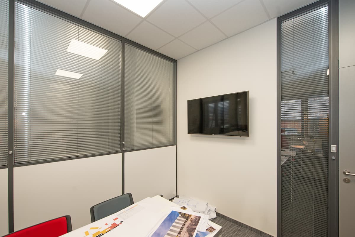 Ukázka řešení, jak rozdělit kancelářský prostor pomocí prosklených příček se žaluziemi v moderní kanceláři.