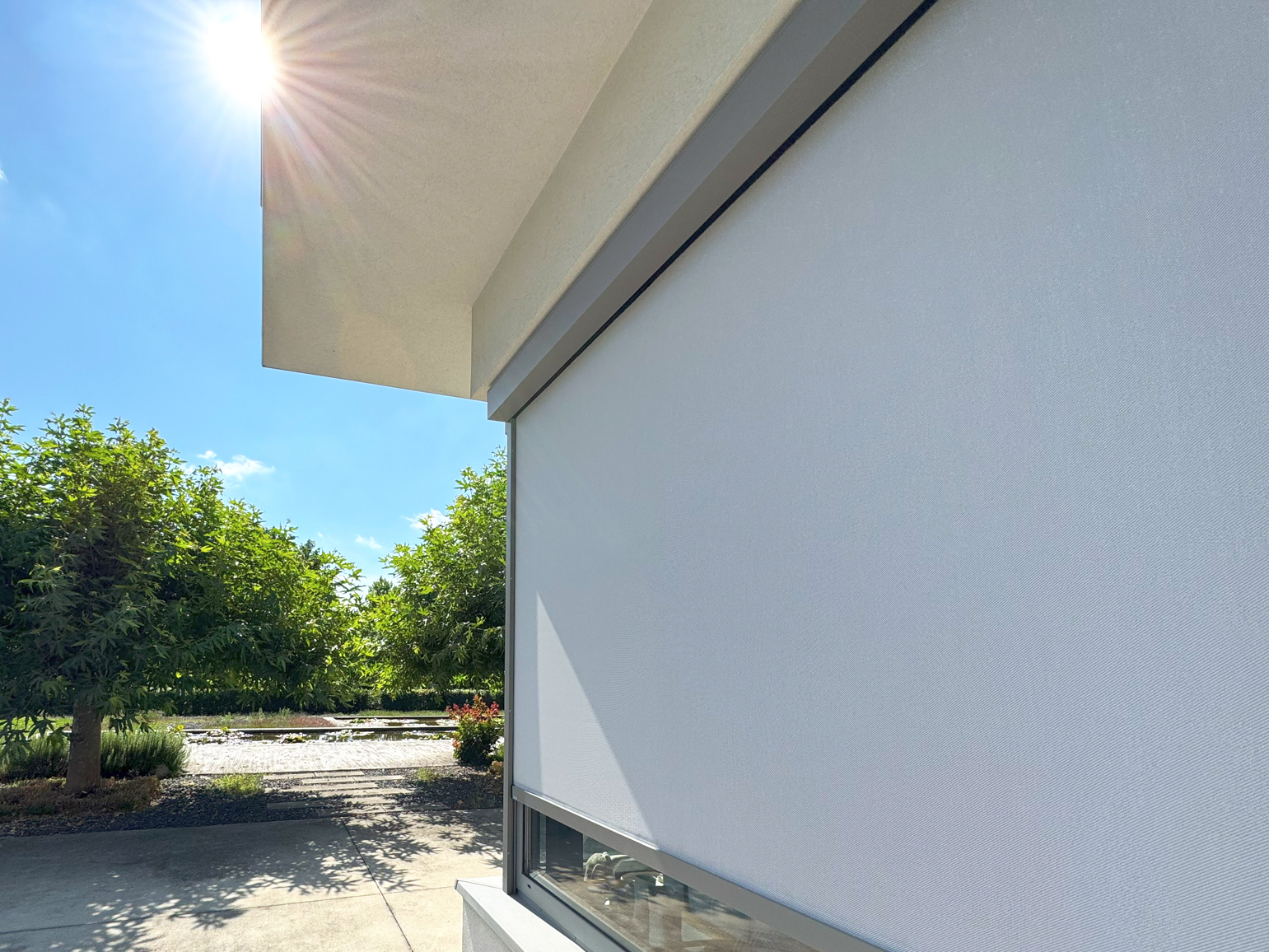 Detail screenové rolety na okně rodinného domu – technická tkanina a vedení v bočních lištách.