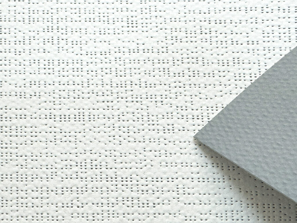 Detail zatemňující screenové látky Soltis Opaque B92 s bílým povrchem a šedou rubovou stranou.