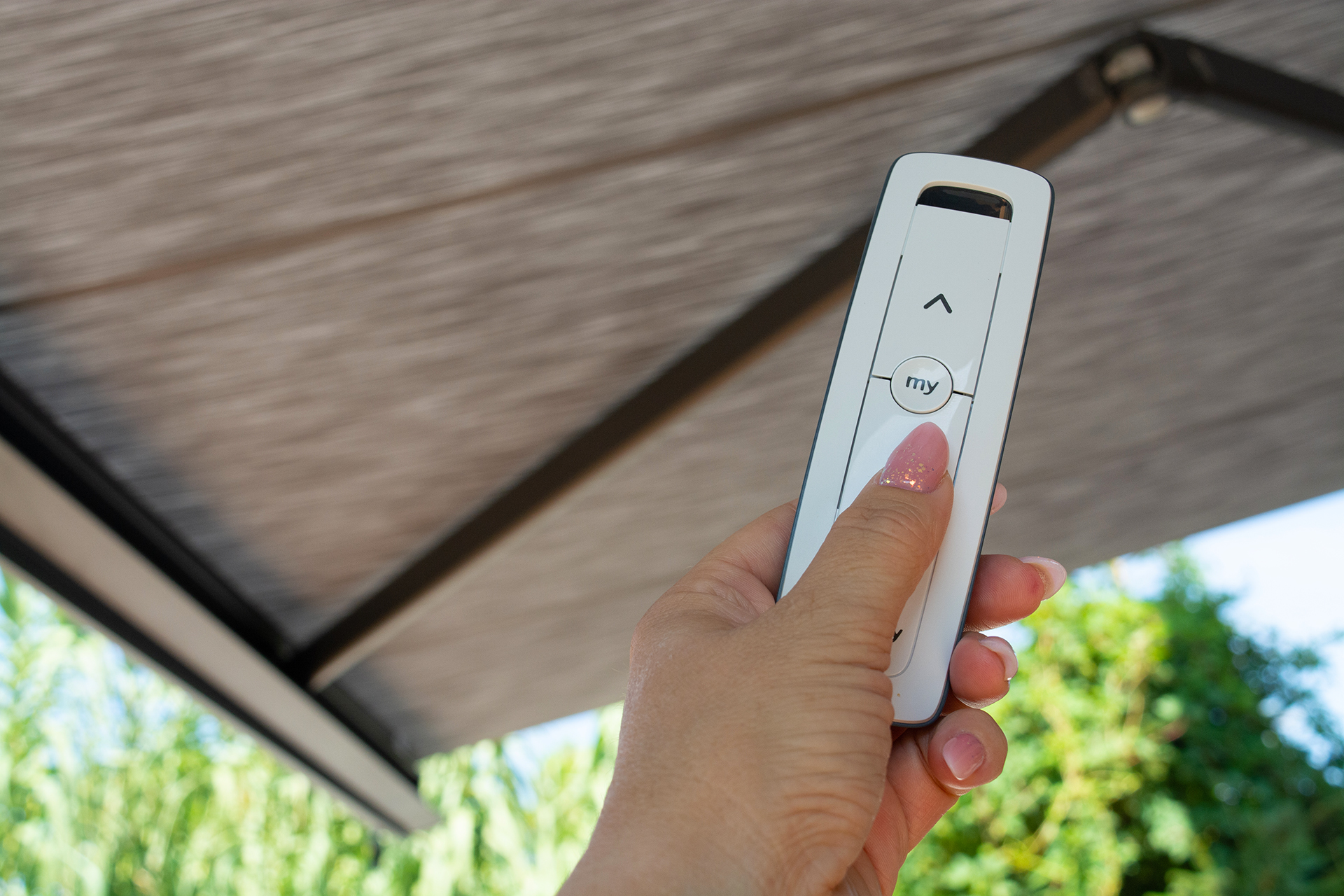 Bílé dálkové ovládání s pozadím šedé markýzy